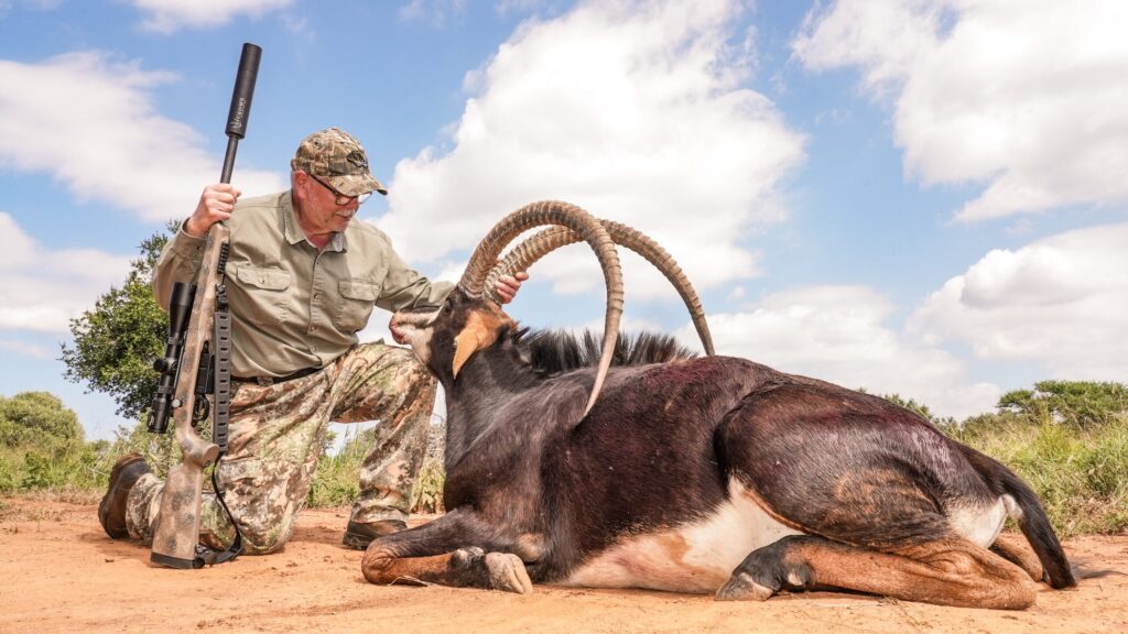 An older hunter beside a sable bull