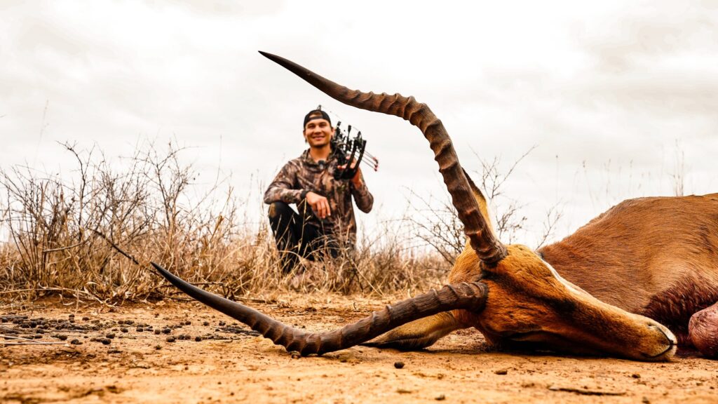 A young bow hunter behind an impala ram