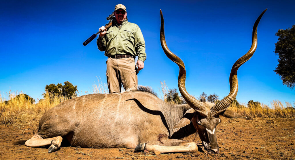A hunter behind a large kudu bull